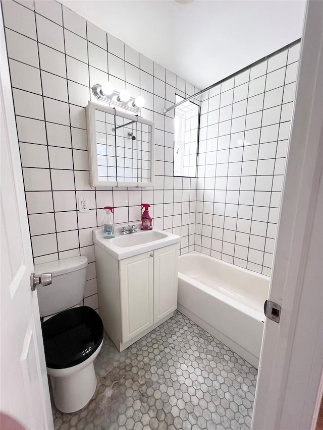 full bathroom featuring toilet, vanity, tile walls, and bathing tub / shower combination