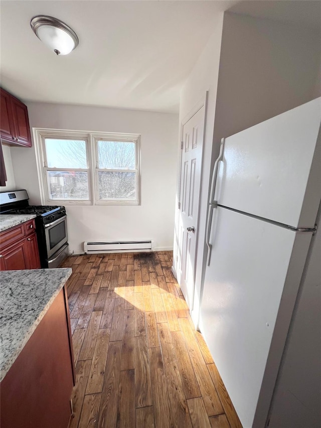 kitchen featuring light stone counters, freestanding refrigerator, hardwood / wood-style flooring, stainless steel gas stove, and a baseboard radiator