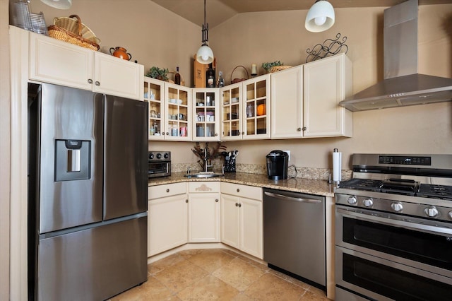 kitchen featuring light stone counters, appliances with stainless steel finishes, wall chimney exhaust hood, white cabinets, and vaulted ceiling