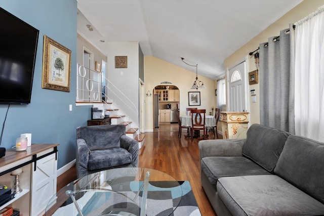 living room featuring baseboards, stairs, lofted ceiling, wood finished floors, and arched walkways