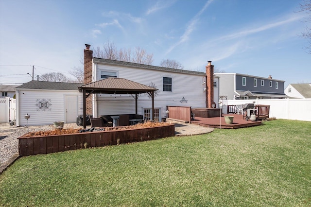 rear view of property with fence, a yard, a chimney, a gazebo, and a deck