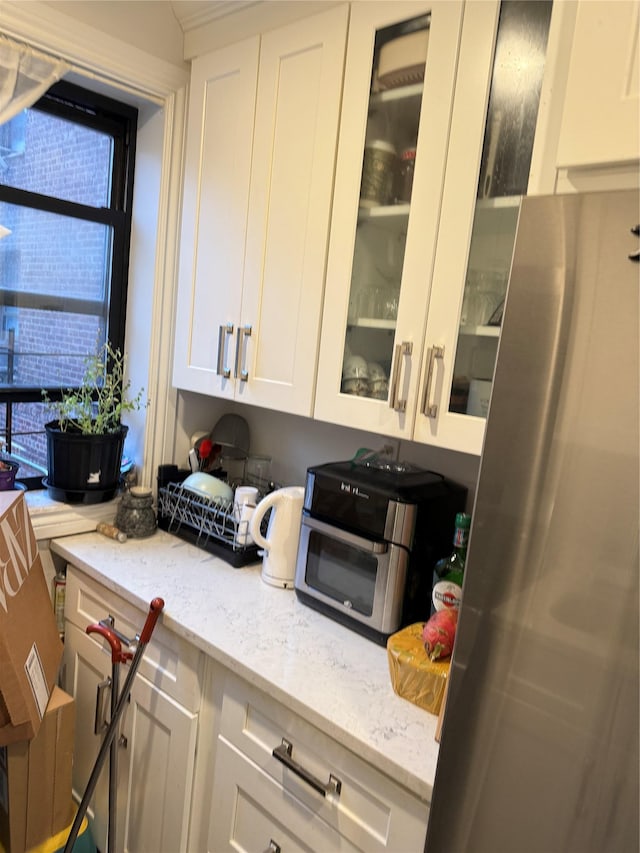 kitchen featuring light stone counters, white cabinetry, and glass insert cabinets