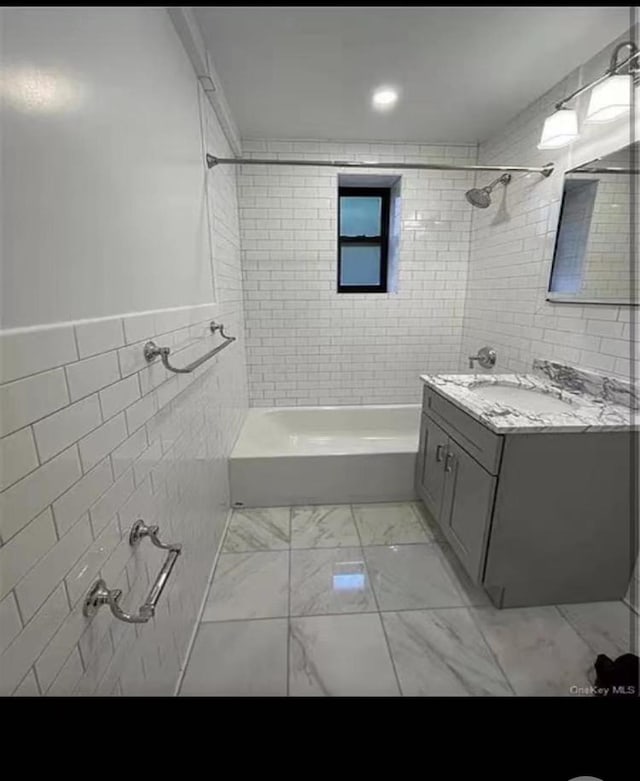 bathroom featuring marble finish floor, shower / bathtub combination, tile walls, and vanity