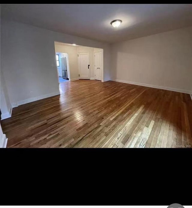 unfurnished living room with baseboards and wood finished floors