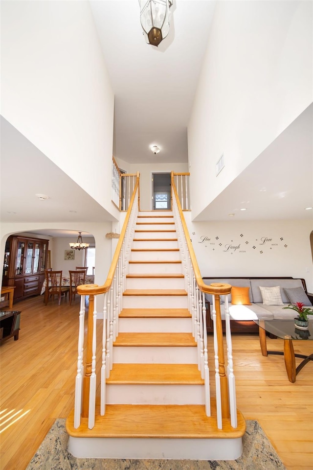 staircase with visible vents, an inviting chandelier, and wood finished floors