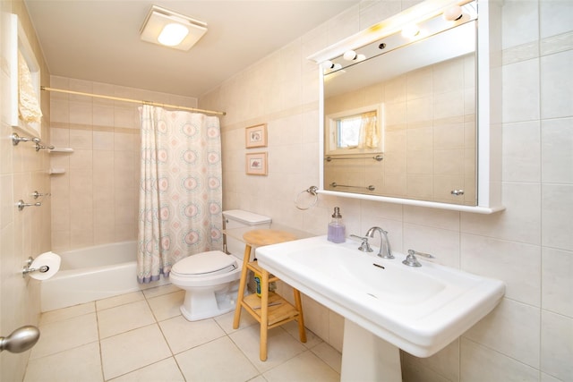 bathroom with toilet, tile patterned floors, shower / bath combination with curtain, tile walls, and a sink