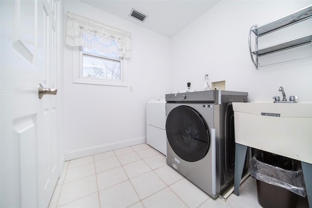 washroom featuring visible vents, washer and dryer, light tile patterned flooring, baseboards, and laundry area