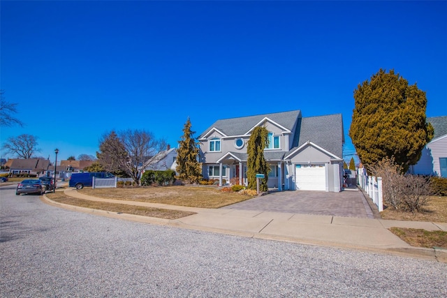 traditional-style house with an attached garage, decorative driveway, and fence