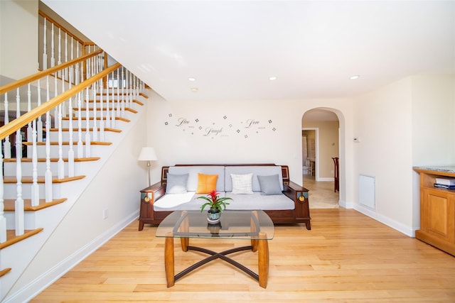 living area featuring baseboards, arched walkways, and light wood-style floors