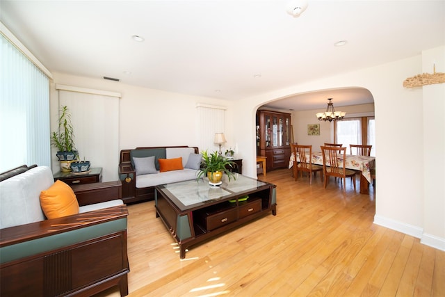 living room featuring baseboards, recessed lighting, an inviting chandelier, light wood-style floors, and arched walkways