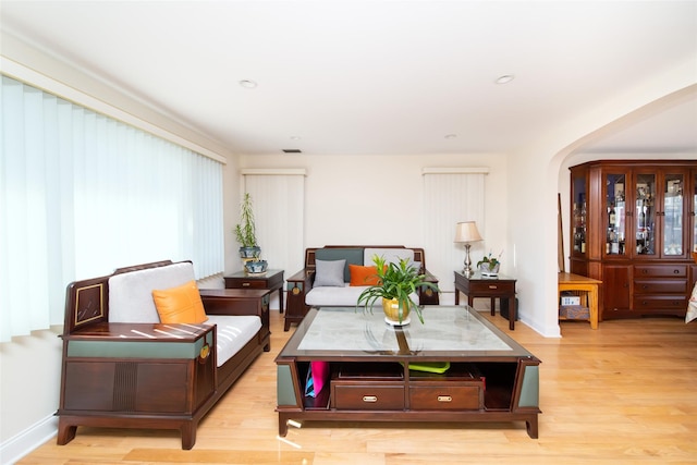 living area with arched walkways, recessed lighting, light wood-type flooring, and baseboards