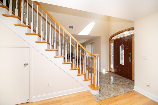 foyer entrance with visible vents, baseboards, wood finished floors, and stairs