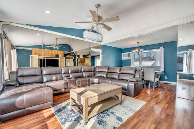 living room with lofted ceiling, ceiling fan with notable chandelier, a wall mounted AC, wood finished floors, and baseboards