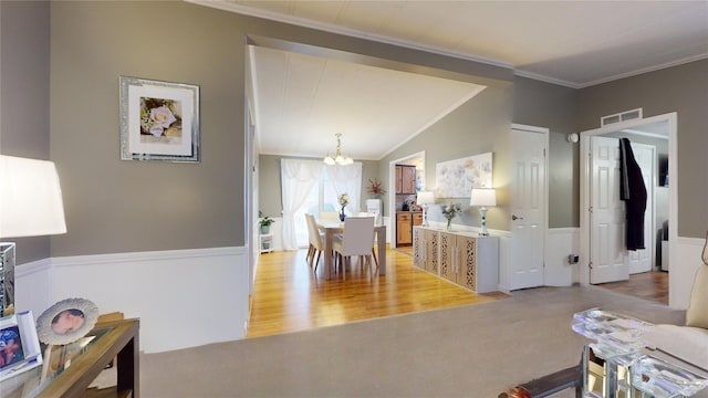 dining area with visible vents, lofted ceiling, wainscoting, crown molding, and a chandelier