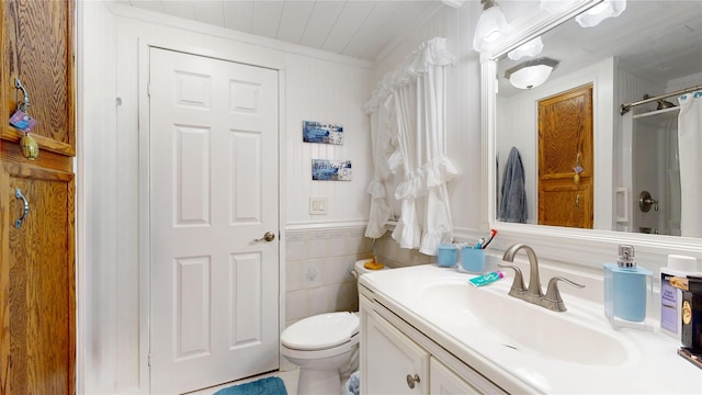 full bathroom with crown molding, toilet, vanity, a shower with curtain, and tile walls