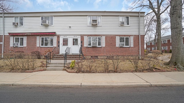 view of front of house with brick siding, crawl space, cooling unit, and entry steps