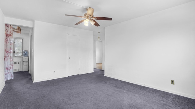 unfurnished bedroom with dark carpet, radiator, and ceiling fan