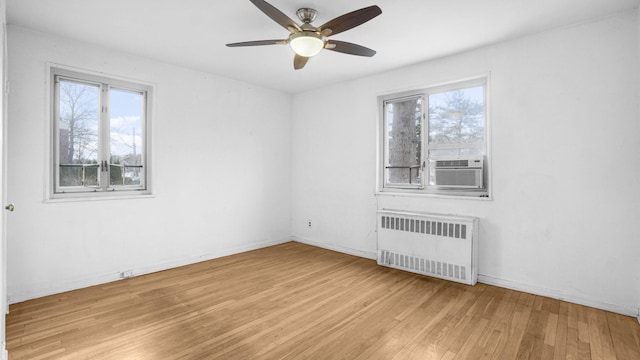 spare room with a wealth of natural light, light wood-type flooring, radiator, and cooling unit