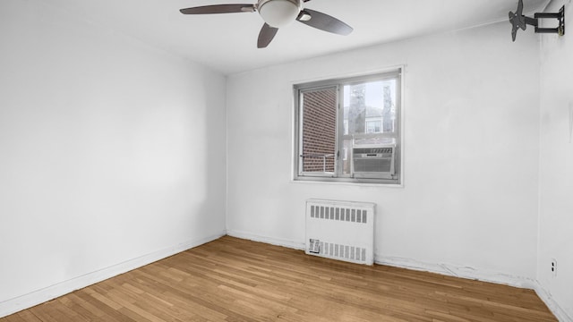 unfurnished room with hardwood / wood-style flooring, cooling unit, radiator, baseboards, and ceiling fan