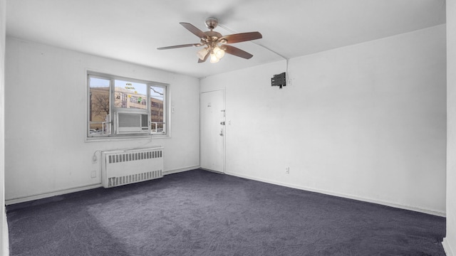 empty room featuring dark carpet, radiator heating unit, and ceiling fan