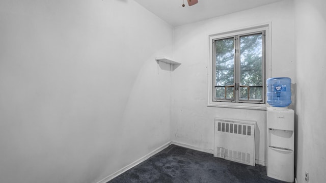 spare room with dark carpet, baseboards, radiator heating unit, and a ceiling fan