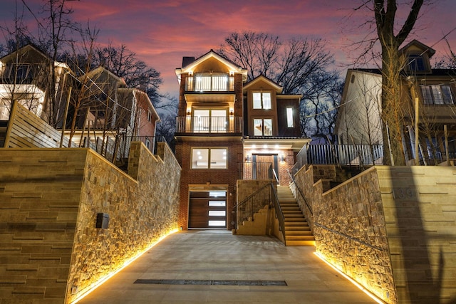 view of front of house with stairs, a balcony, and brick siding