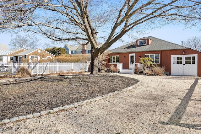 view of front of home with a garage, roof with shingles, and fence