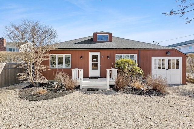 view of front of property with roof with shingles and fence