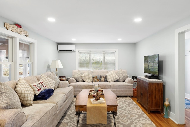 living area featuring recessed lighting, light wood-type flooring, baseboards, and a wall unit AC