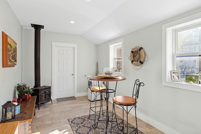 dining space featuring recessed lighting, baseboards, a wood stove, and lofted ceiling