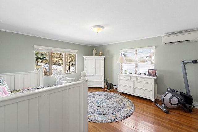 bedroom featuring baseboards, wood finished floors, crown molding, and a wall unit AC