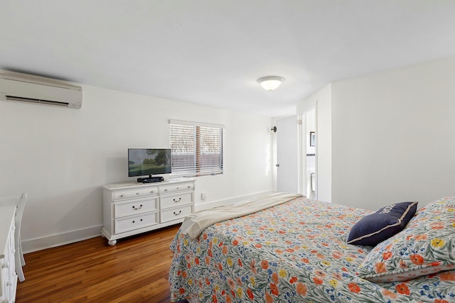 bedroom with a wall unit AC, wood finished floors, and baseboards