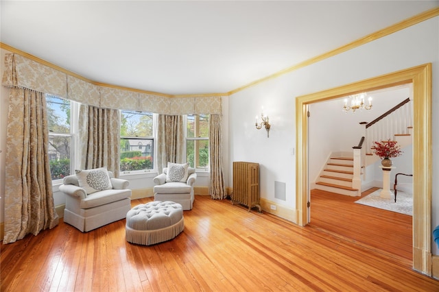 sitting room with a notable chandelier, light wood finished floors, radiator, a wealth of natural light, and stairway