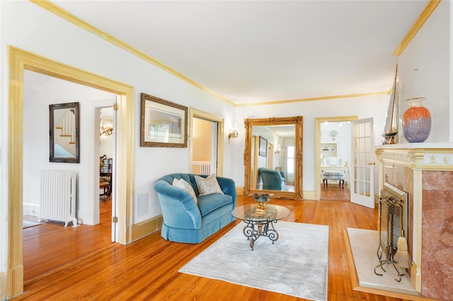 living room with radiator, ornamental molding, baseboards, and wood finished floors