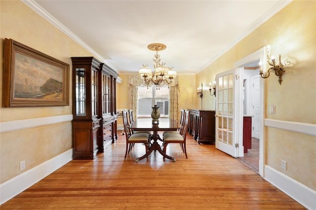 dining room featuring crown molding, light wood finished floors, baseboards, and a notable chandelier