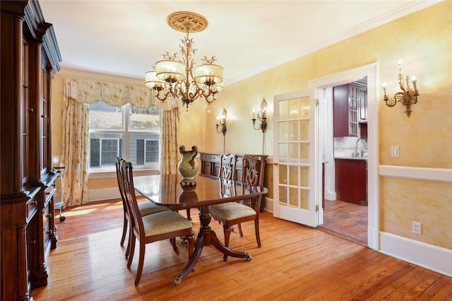 dining area with baseboards, an inviting chandelier, ornamental molding, and light wood finished floors