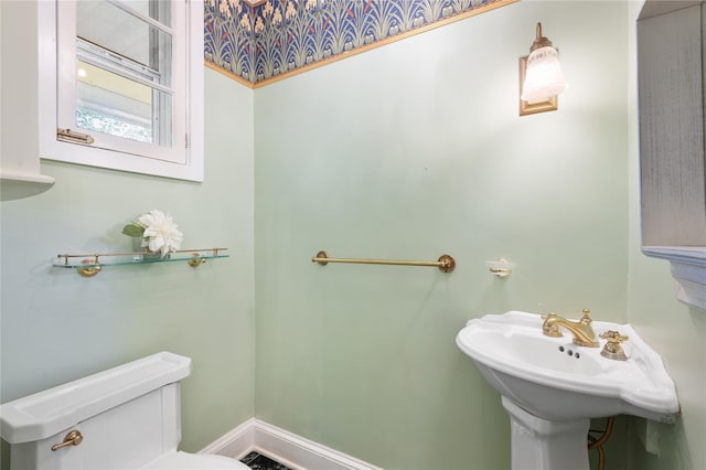 half bath featuring baseboards and toilet