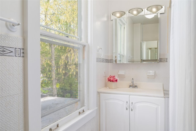 bathroom featuring vanity, plenty of natural light, and tile walls