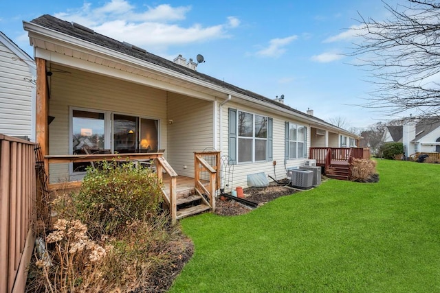 rear view of house with a lawn, a wooden deck, and central AC