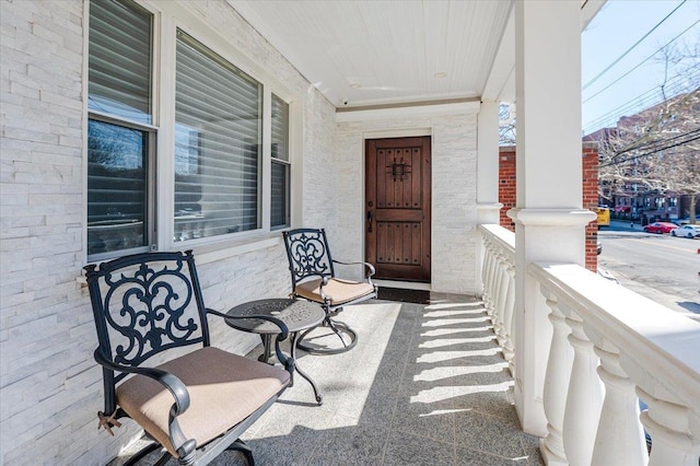 view of exterior entry featuring brick siding and a porch