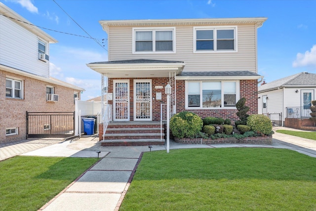 view of front of home featuring a front lawn, fence, covered porch, a shingled roof, and brick siding