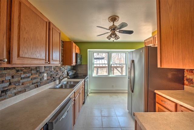 kitchen featuring light tile patterned floors, a sink, decorative backsplash, stainless steel appliances, and a baseboard heating unit