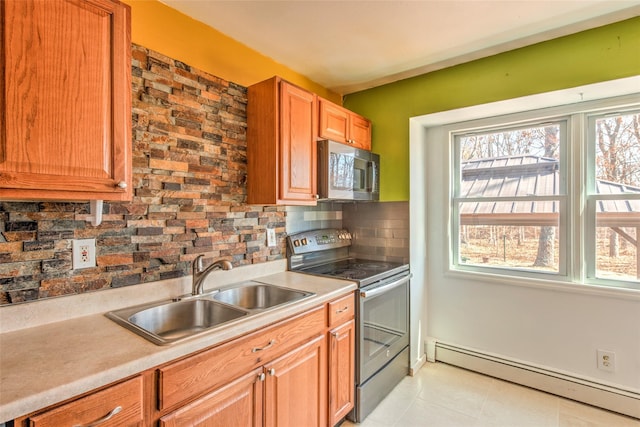 kitchen featuring light countertops, baseboard heating, decorative backsplash, stainless steel appliances, and a sink