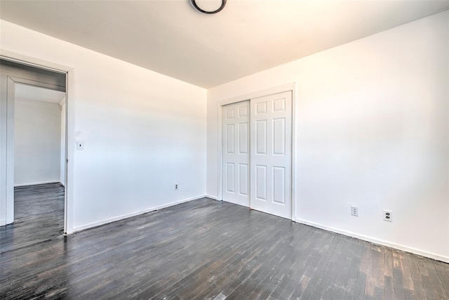 unfurnished bedroom featuring a closet, baseboards, and dark wood-style floors