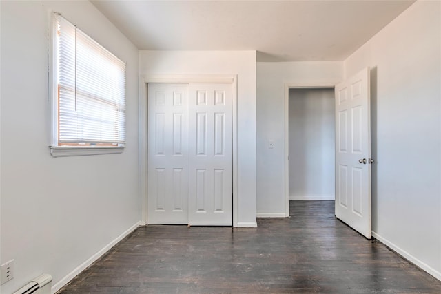 unfurnished bedroom with baseboards, baseboard heating, and dark wood finished floors