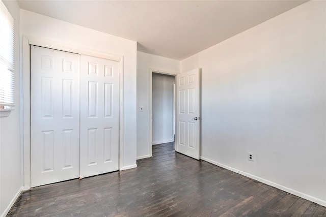 unfurnished bedroom featuring dark wood-style floors, a closet, and baseboards