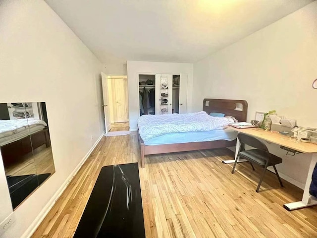 bedroom with light wood-style floors, baseboards, and a closet