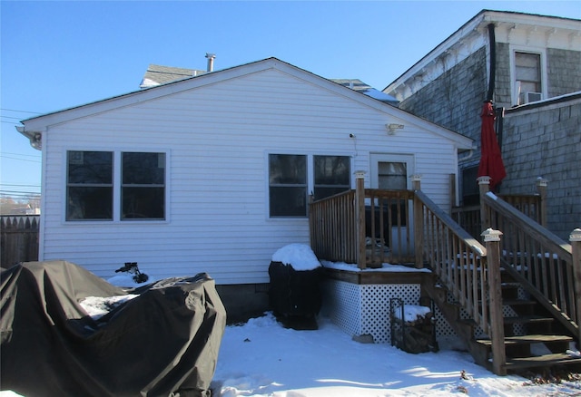 snow covered rear of property featuring fence