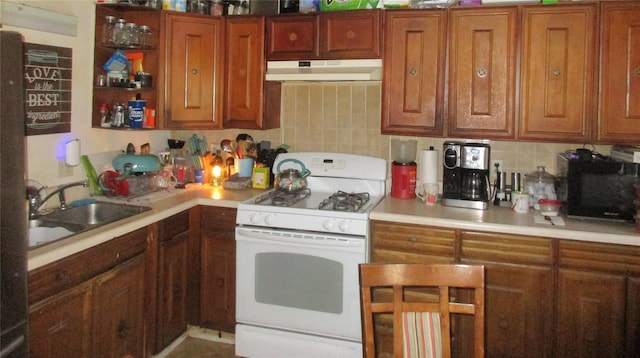 kitchen featuring under cabinet range hood, backsplash, white gas stove, and a sink