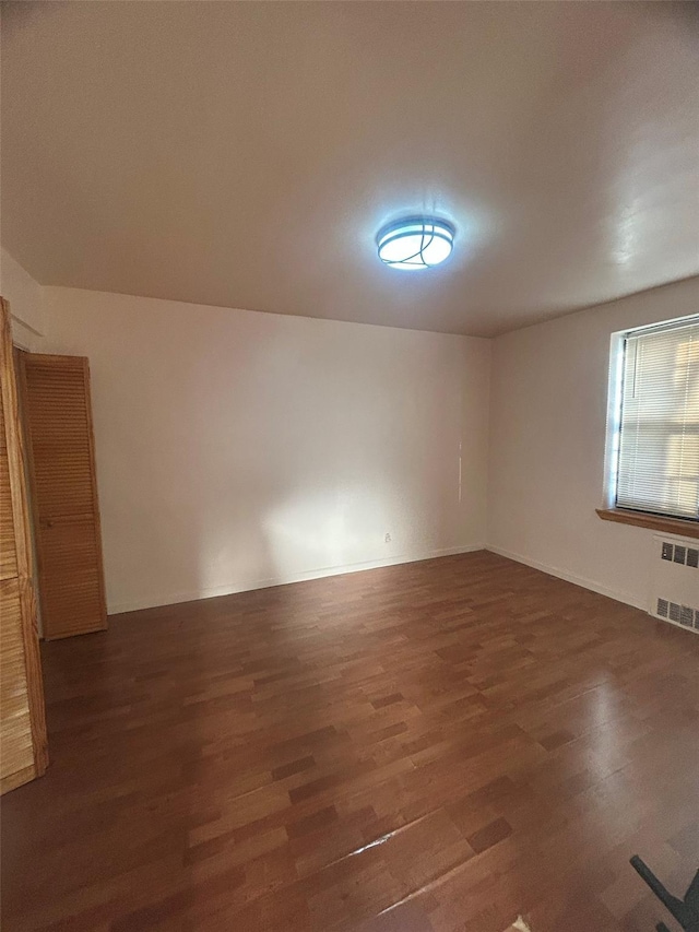 spare room featuring wood finished floors and radiator heating unit